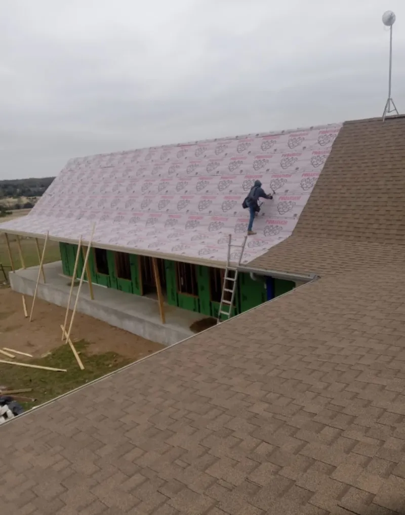 Worker preparing underlayment for a metal roof installation in Battle Creek